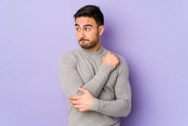 Mor arka planda soyutlanmış, kafası karışmış, şüpheli ve kararsız genç bir beyaz adam..