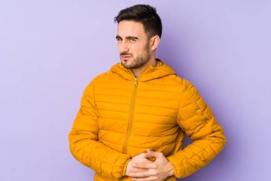 Mor arka planda karaciğer ağrısı çeken, karnı ağrıyan genç beyaz bir adam..