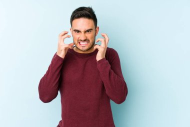 Mavi arka planda izole edilmiş genç beyaz adam gergin elleriyle çığlık atıyor..