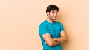 Bej arka planda izole edilmiş genç adam şüpheli, belirsiz, seni muayene ediyor..