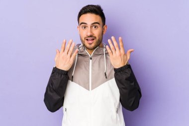 Mor arka planda izole edilmiş genç beyaz adam on numarayı elleriyle gösteriyor..