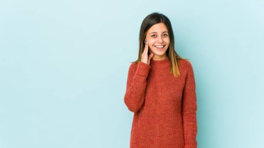 Mavi arka planda izole edilmiş genç bir kadın yüksek sesle bağırıyor, gözleri açık ve elleri gergin tutuyor..