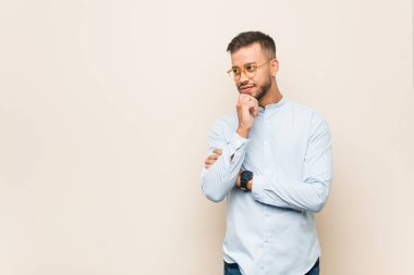 Genç Güney Asyalı iş adamı rahatlamış fotokopi alanına bakan bir şey düşünüyor..