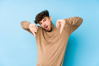 Genç Arap adam kendini izole edip baş parmağını aşağı gösteriyor ve hoşlanmadığını ifade ediyor..