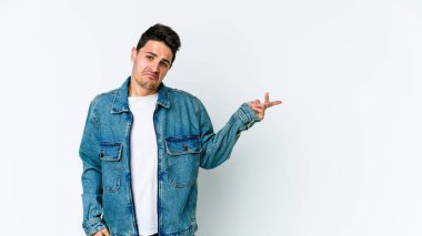 Beyaz arka planda izole edilmiş genç beyaz bir adam sorgulama sırasında omuz silkiyor ve şüphe duyuyor..