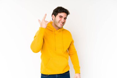 Beyaz arka planda izole edilmiş genç adam parmaklarıyla kaya hareketi gösteriyor.