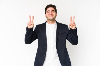 Beyaz arka planda izole edilmiş genç iş adamı zafer işareti gösteriyor ve gülümsüyor..