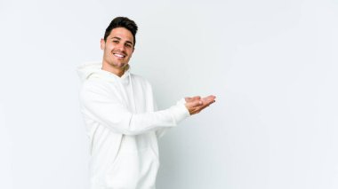 Beyaz arka planda izole edilmiş beyaz tenli genç bir adam palmiyesinde bir kopya alanı tutuyor..