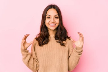 Latin kökenli genç bir kadın avuçlarıyla bir şey tutup kameraya sunuyor..