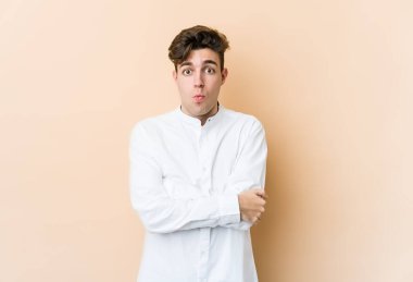 Beyazların arka planında izole edilmiş genç beyaz adamın yanakları şişer, yorgun bir ifadesi vardır. Yüz ifadesi kavramı.