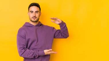 Kafkasyalı genç adam sarı fırında iki eliyle bir şey tutuyor, ürün sunumu..