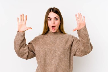 Beyaz arka planda izole genç beyaz kadın hoş bir sürpriz alıyor, heyecanlı ve el kaldırıyor..