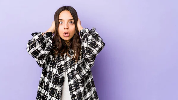 Genç, melez, İspanyol bir kadın. Kulaklarını ellerinle kapatıyor. Gürültülü sesler duymamaya çalışıyor..