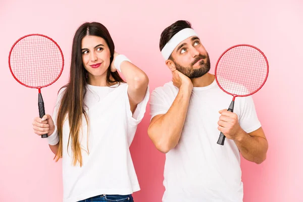 Casal Jovem Jogando Badminton Isolado Tocando Parte Trás Cabeça Pensando — Fotografia de Stock