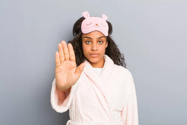 身穿睡衣和睡眠面具的年轻的非洲裔美国女人站在那里 伸出的手显示出停止的迹象 阻止了你 — 图库照片