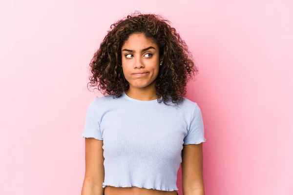 ピンクの背景をした若いアフリカ系アメリカ人の女性は 混乱し 疑問と不安を感じています — ストック写真