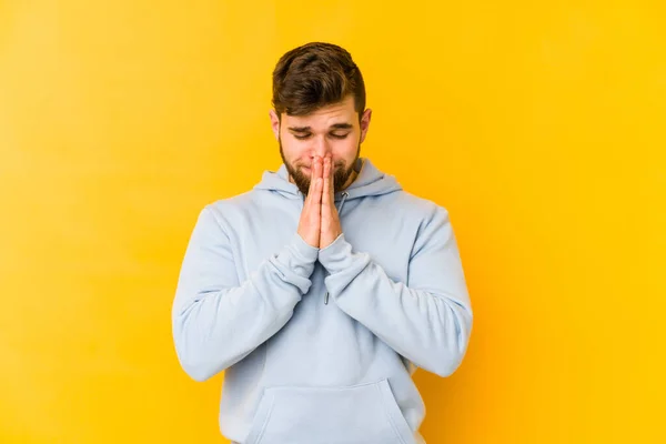 Joven Hombre Caucásico Aislado Sobre Fondo Amarillo Cogido Mano Orar —  Fotos de Stock