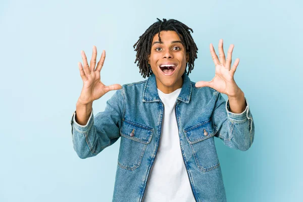 Kot ceket giyen genç siyah adam hoş bir sürpriz yaşıyor, heyecanlı ve el kaldırıyor..