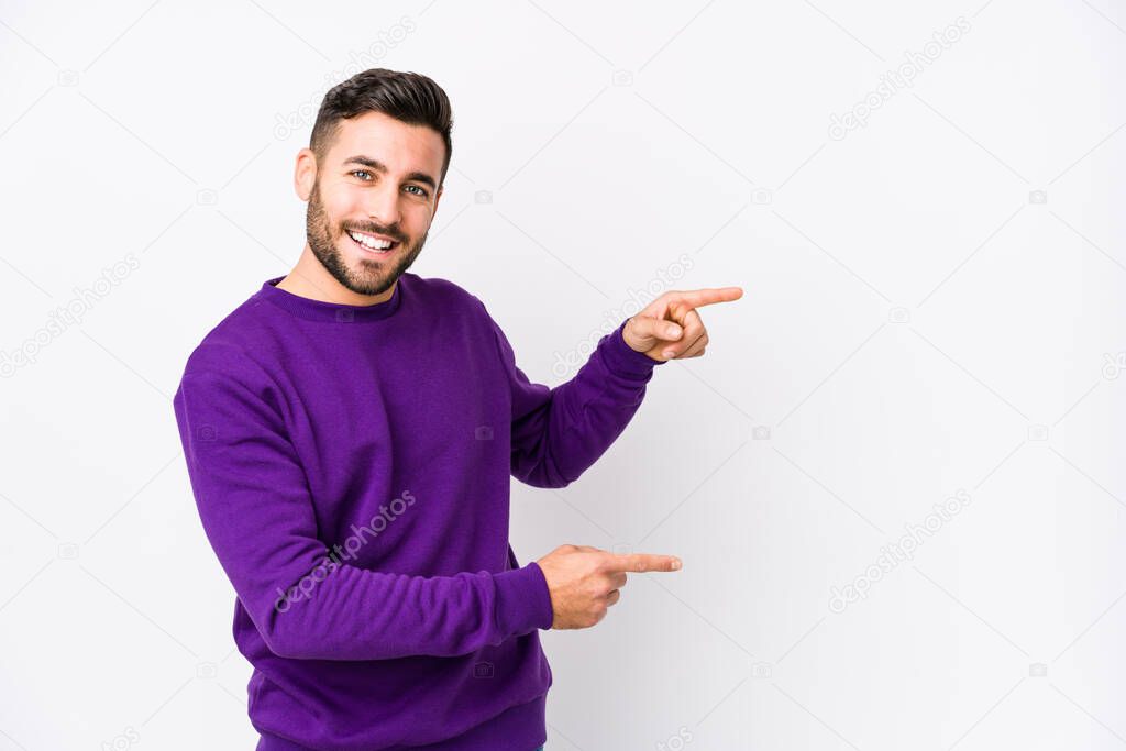 Young caucasian man against a white background isolated excited pointing with forefingers away.