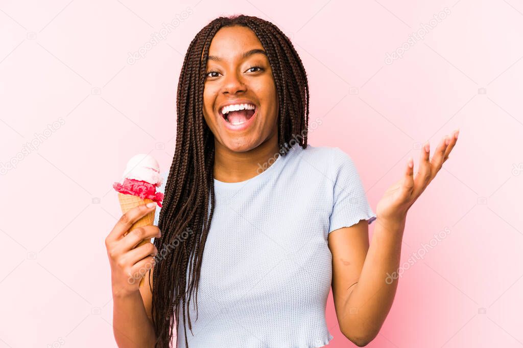 Young african american woman holding an ice cream isolated receiving a pleasant surprise, excited and raising hands.