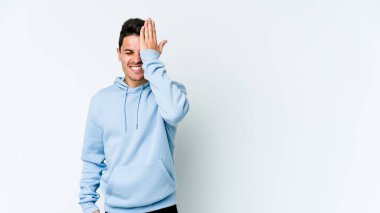 Beyaz arka planda izole edilmiş genç beyaz bir adam bir şeyi unutuyor. Alnına avuç içi ve gözlerini kapayarak vuruyor..