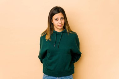 Bej arka planda izole edilmiş genç bir kadın üzgün, ciddi bir yüz, mutsuz ve hoşnutsuz..