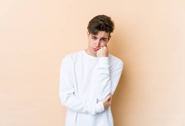 Bej arka planda izole edilmiş, üzgün ve dalgın hisseden, fotokopi alanına bakan genç beyaz bir adam..