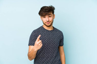 Mavi bir arka planda izole edilmiş genç bir Arap sanki seni davet ediyormuş gibi parmağıyla işaret ediyor..