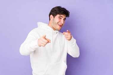 Mor arka planda izole edilmiş genç adam parmaklarıyla öne doğru işaret ediyor..