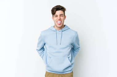 Beyaz arka planda izole edilmiş genç beyaz bir adam. Komik ve dost canlısı bir dil uzatıyor..