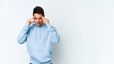 Beyaz arka planda izole edilmiş genç beyaz bir adam tapınaklara dokunuyor ve başı ağrıyor..