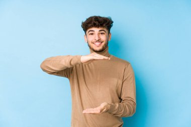 Genç Arap adam iki eliyle bir şey tutuyor, ürün sunumu..