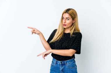 Beyaz arka planda izole edilmiş genç sarışın kadın işaret parmaklarıyla fotokopi alanını işaret ederek heyecan ve arzuyu ifade ediyor..