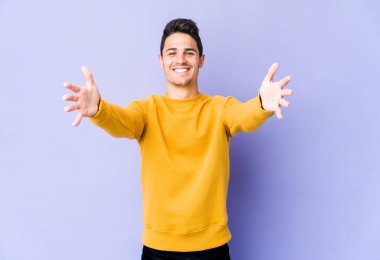 Mor arka planda izole genç beyaz adam kameraya sarıldığı için kendinden emin hissediyor..