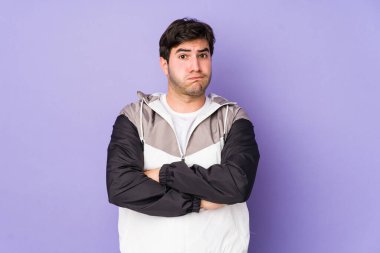 Mor arka planda izole edilmiş genç adamın yanakları şişer, yorgun bir ifadesi vardır. Yüz ifadesi kavramı.