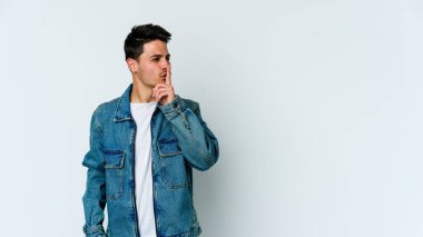 Beyaz arka planda izole edilmiş genç beyaz bir adam ya sır saklıyor ya da sessizlik istiyor..