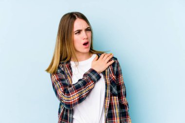 Mavi arka planda izole edilmiş, omuz ağrısı olan beyaz bir kadın..