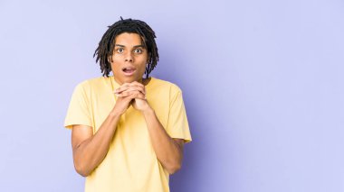 Afro-Amerikan Rasta 'lı genç adam şans için dua ediyor, şaşırmış ve ağzını açıyor..