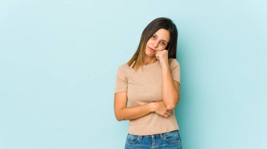 Mavi arka planda izole edilmiş genç bir kadın tekrarlanan bir görevden yoruldu..