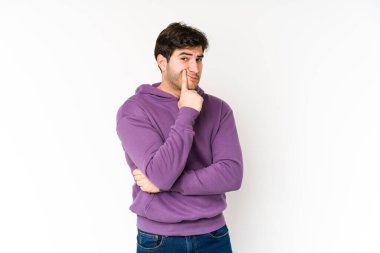 Beyaz arka planda izole edilmiş genç adam kameraya alaycı bir ifadeyle bakıyor..