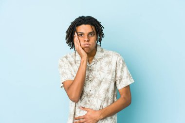 Genç Afrikalı Amerikalı Rasta adamın yanakları şişiyor, yorgun bir ifadesi var. Yüz ifadesi kavramı.