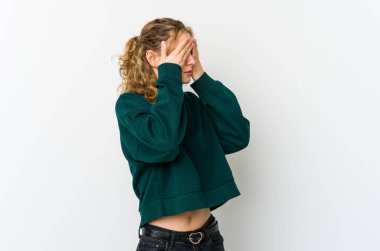 Beyaz arka plandaki genç beyaz kadın elleriyle gözlerini kapatmaktan korkuyor..