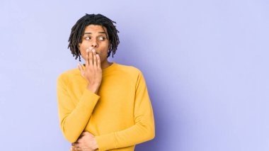 Rasta saç stili giyen genç siyah adam esniyor. Ağzı eliyle kapatan yorgun bir hareket sergiliyor..