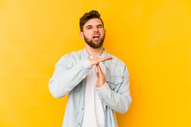 Sarı arka planda izole edilmiş genç beyaz adam bir mola hareketi gösteriyor..