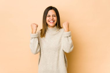 Bej arka planda yalnız kalmış genç bir kadın tasasız ve heyecanlı bir şekilde tezahürat yapıyor. Zafer konsepti.