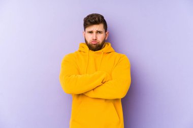 Mor arka planda izole edilmiş genç adamın yanakları şişer, yorgun bir ifadesi vardır. Yüz ifadesi kavramı.