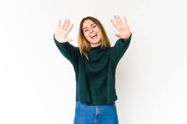 Beyaz arka planda izole edilmiş beyaz tenli genç kadın on numarayı elleriyle gösteriyor..