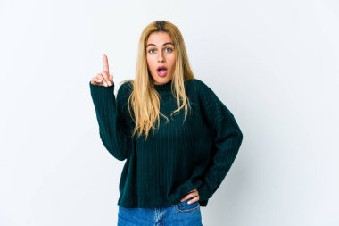Beyaz arka planda izole edilmiş genç sarışın kadın ağzı açık bir şekilde yukarı işaret ediyor..