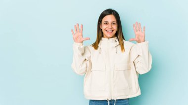 Mavi arka planda izole edilmiş genç bir kadın on numarayı elleriyle gösteriyor..