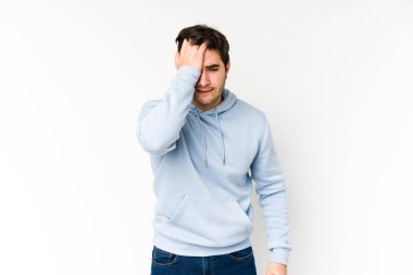 Beyaz arka planda izole edilmiş genç bir adam bir şeyi unutuyor. Alnına avuç içi ile vuruyor ve gözlerini kapıyor..